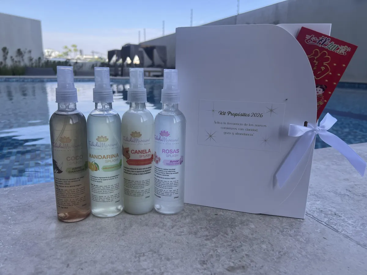 Grupo diverso de personas con los ojos cerrados, tomados de las manos en círculo, cada uno con un Kit de Abundancia 2026 frente a ellos; fondo fucsia suave, expresando unidad y esperanza.