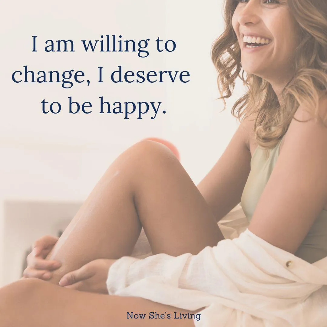 A smiling woman featured on Now She’s Living Instagram, paired with the affirmation 'I am willing to change, I deserve to be happy.