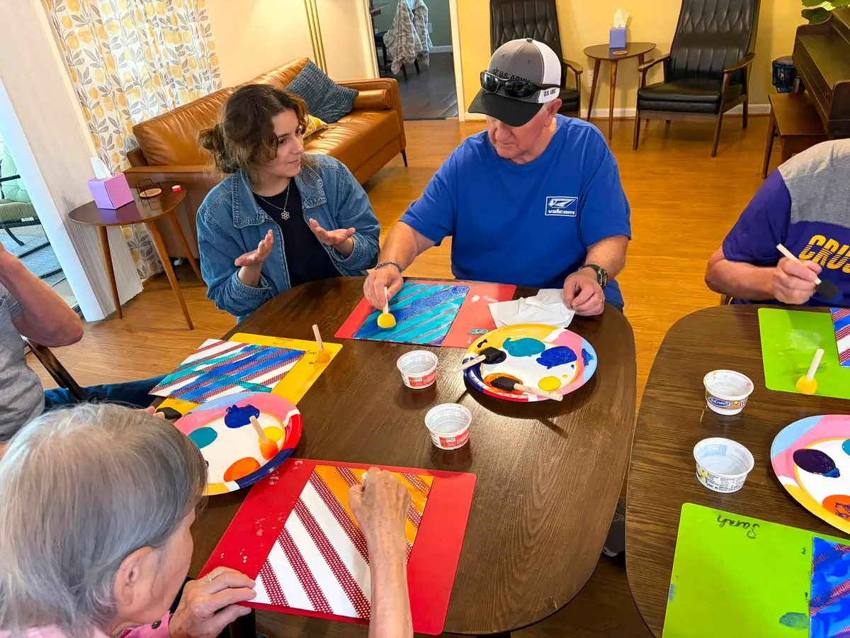 DEC participants and a team member painting together during an enrichment activity