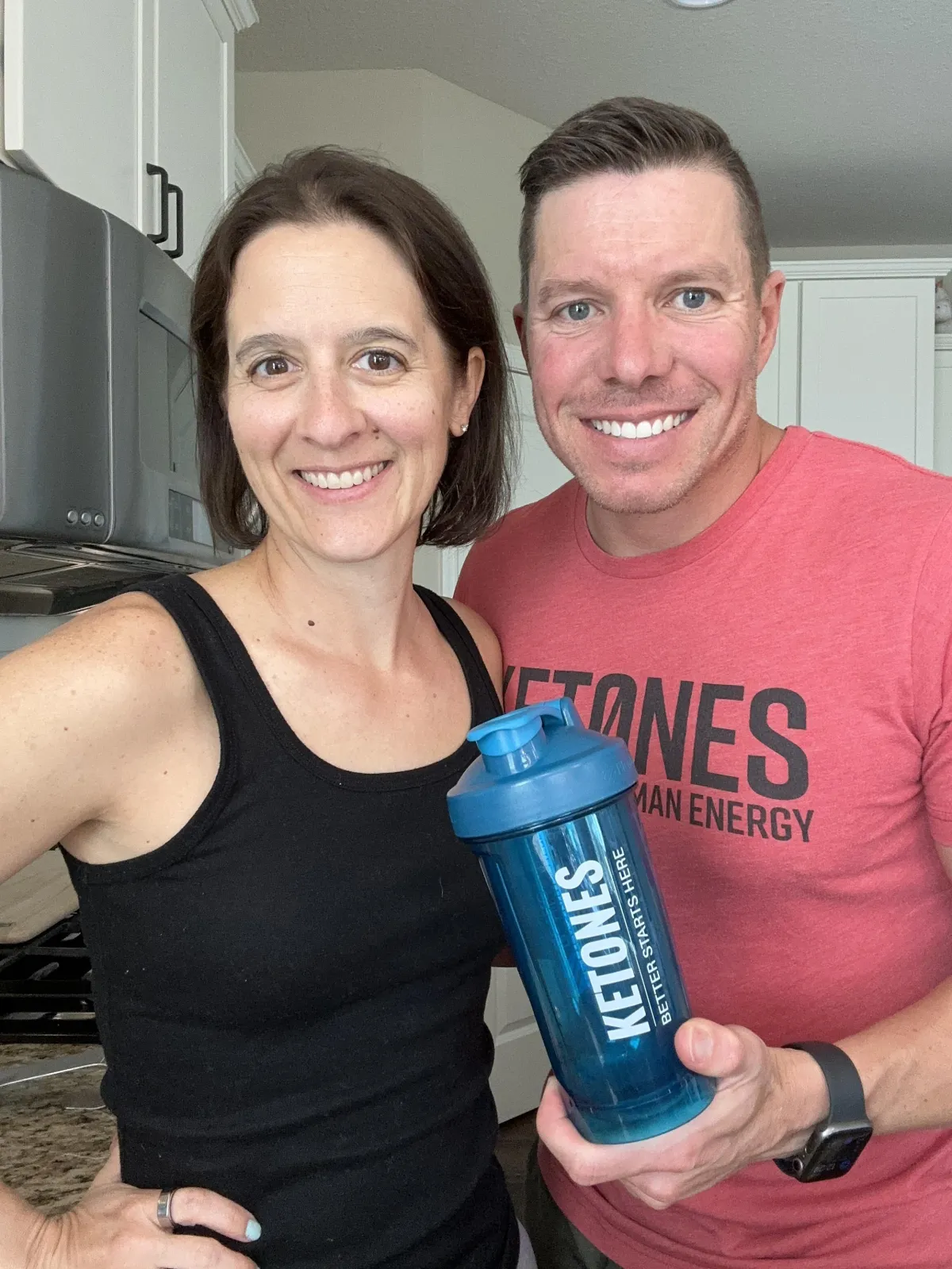 Happy couple dressed in fitness gear with arms around each other, enjoying time outdoors, representing wellness, connection, and support.