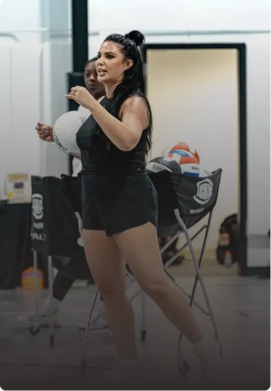 Framed portrait photo of a female volleyball coach demonstrating a move on the court.
