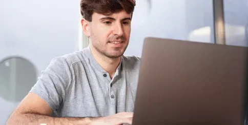 Man working on a laptop in a modern office for digital project management and online collaboration