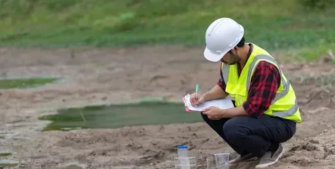 Environmental surveyor collecting hydrology data near a waterbody for site assessment