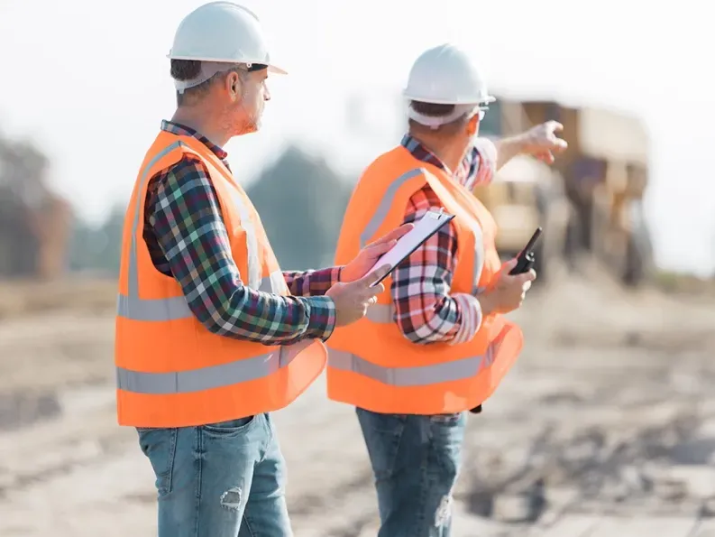 Construction workers reviewing plans and supervising site activities for land development