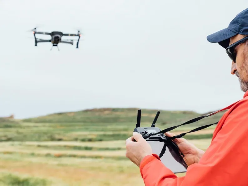 Drone operator flying a professional drone for surveying and mapping rural landscapes