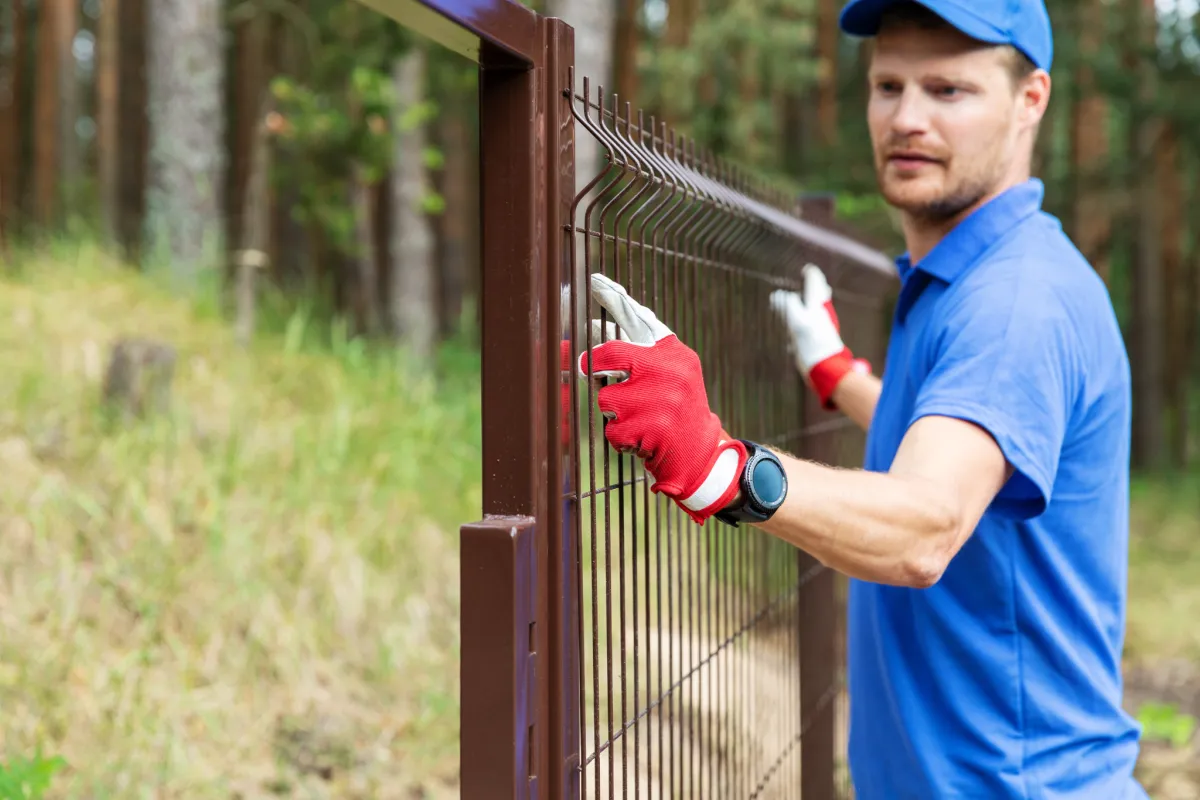 Worker installing metal fence, providing professional fence installation services in Roanoke Virginia