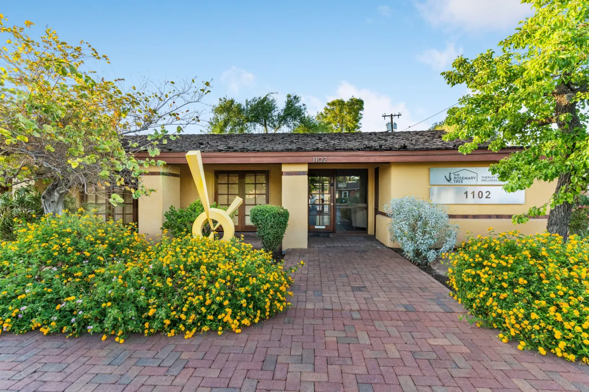 A cozy, home-like reception or lounge area with soft seating and woven wall hangings, creating a relaxed, welcoming atmosphere.