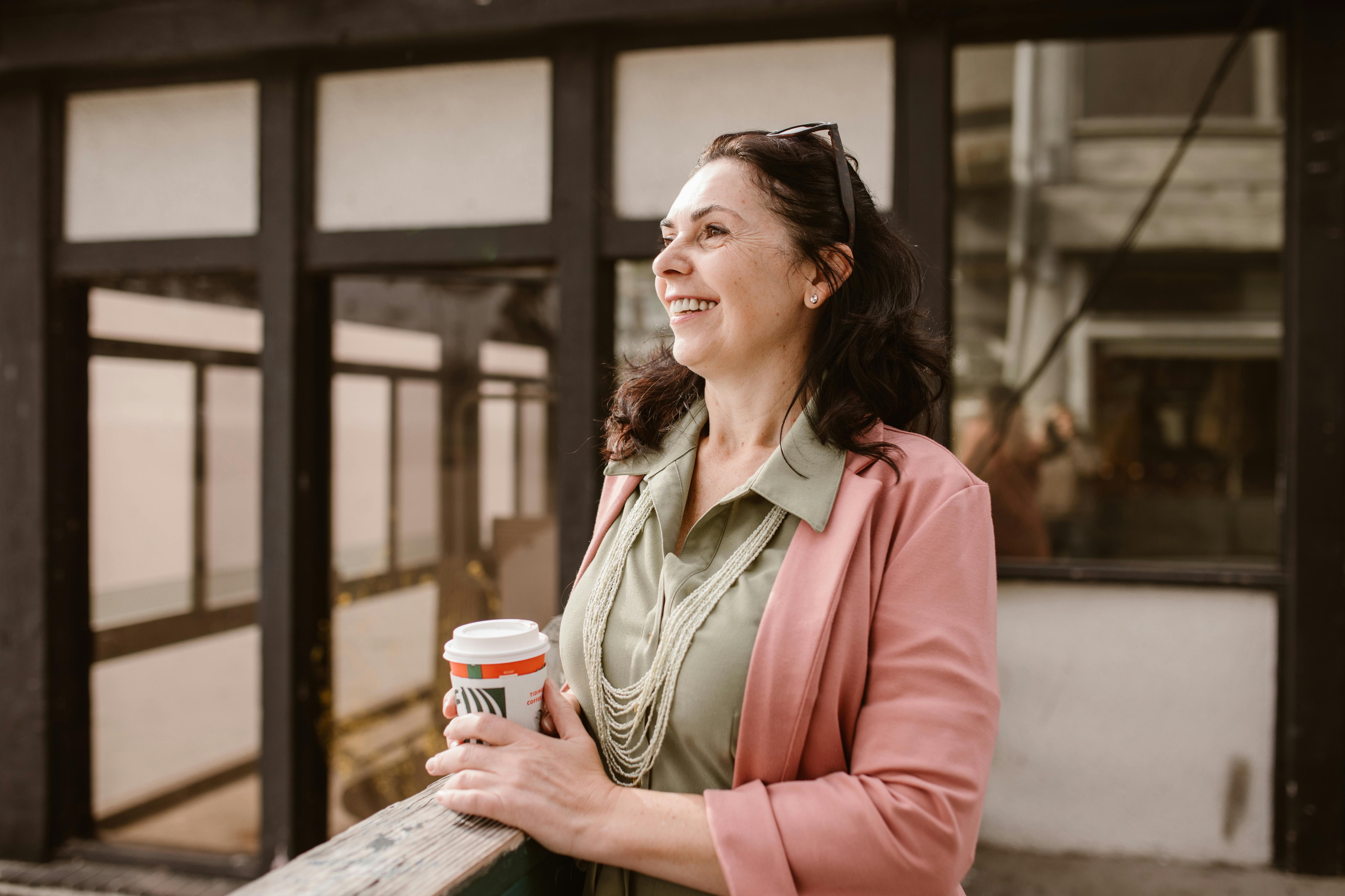 Smiling midlife woman holding a cup of coffee in a relaxed setting