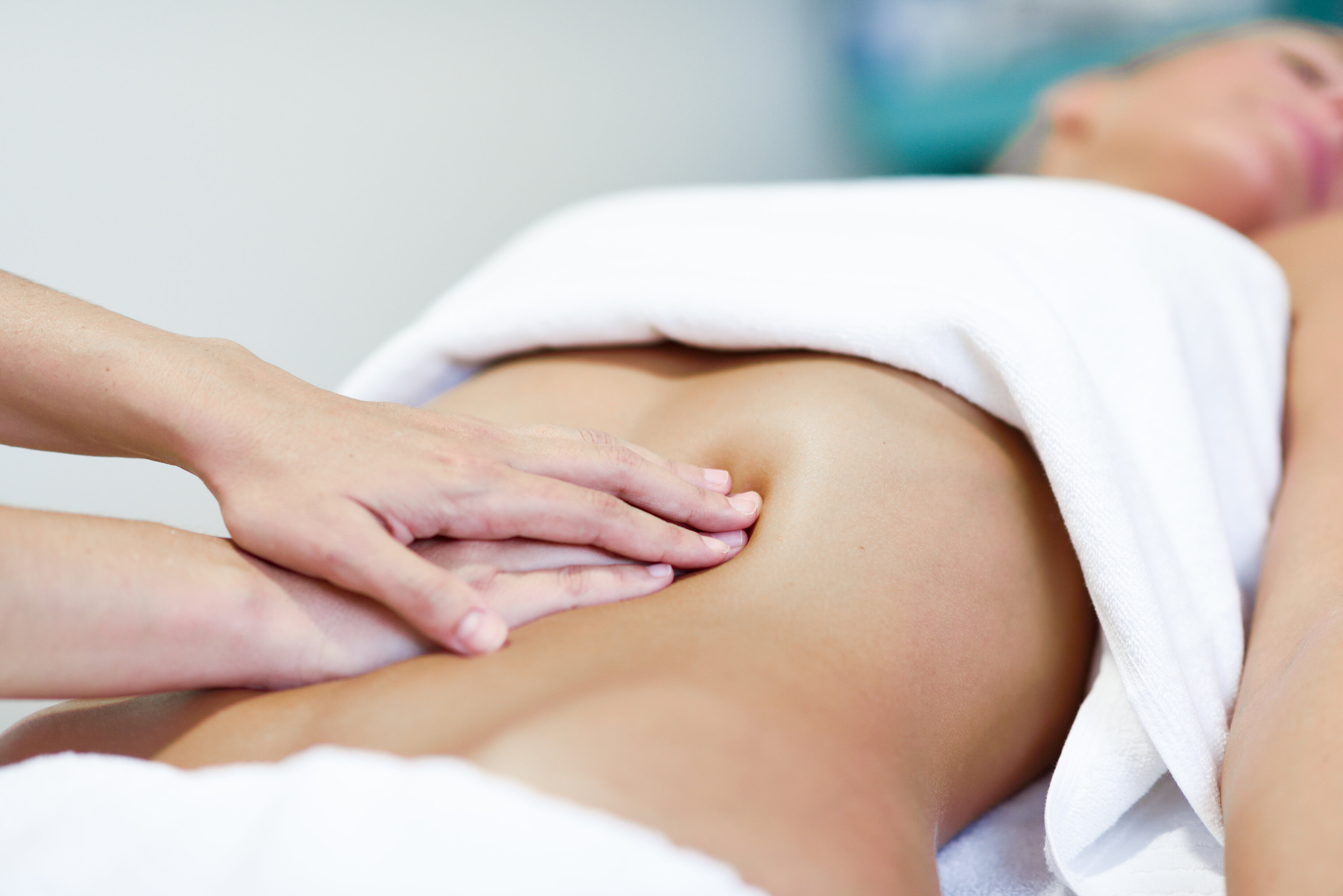 Therapist performing lymphatic drainage in a warm, neutral clinic