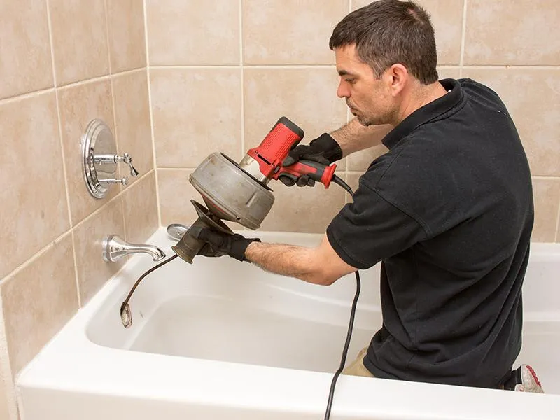 plumber cleaning a bathtub drain