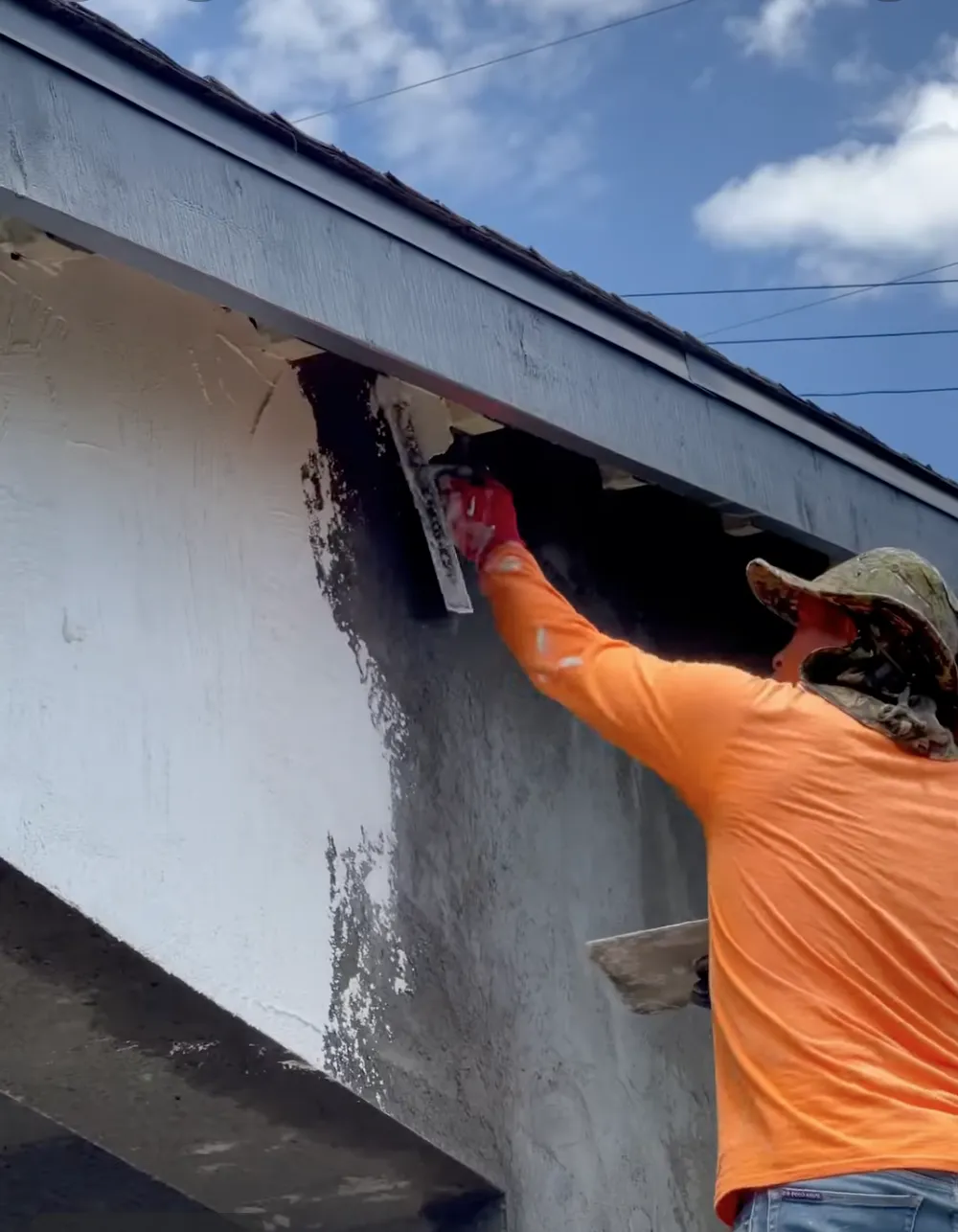 Man with orange shirt applying new stucco
