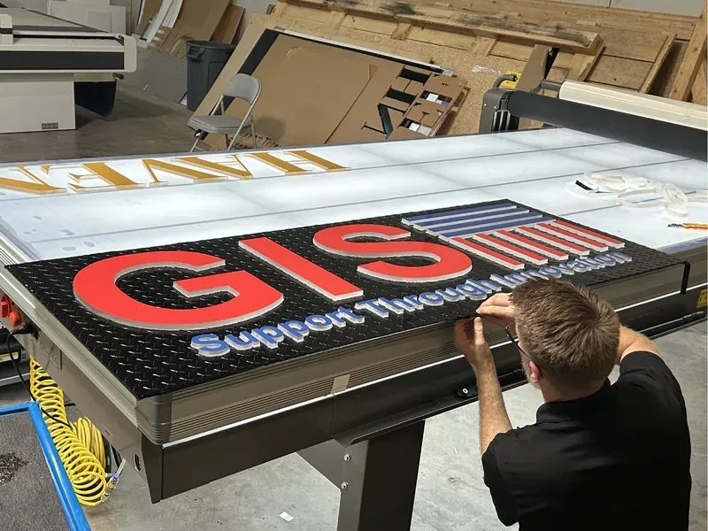 Close-up of a technician assembling a large red and black dimensional GIST logo sign