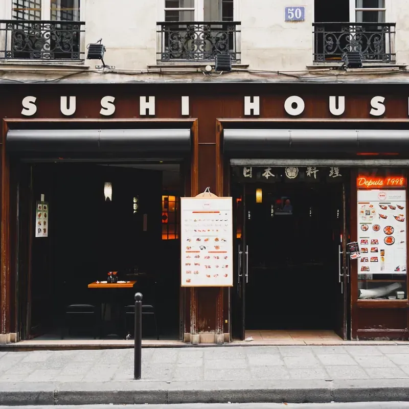 Sushi House restaurant storefront with a minimalist dark wood facade and illuminated signage