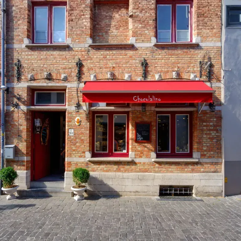 Charming brick restaurant exterior featuring a bright red promotional awning and custom window identification signs