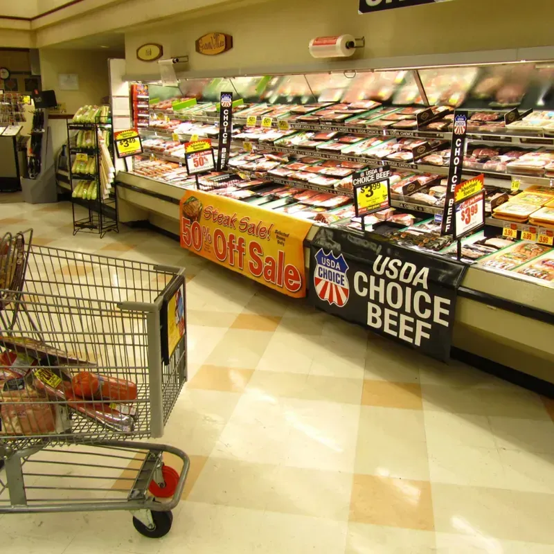 Retail grocery store interior featuring custom promotional signage for USDA Choice Beef and meat department sales