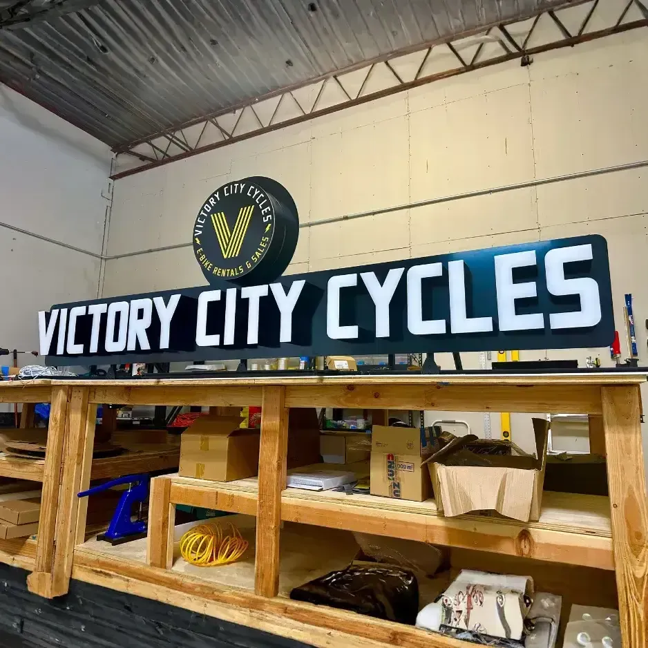 Large blue and yellow 'Victory City Church' circular logo and channel letter sign mounted high on an interior industrial-style wall