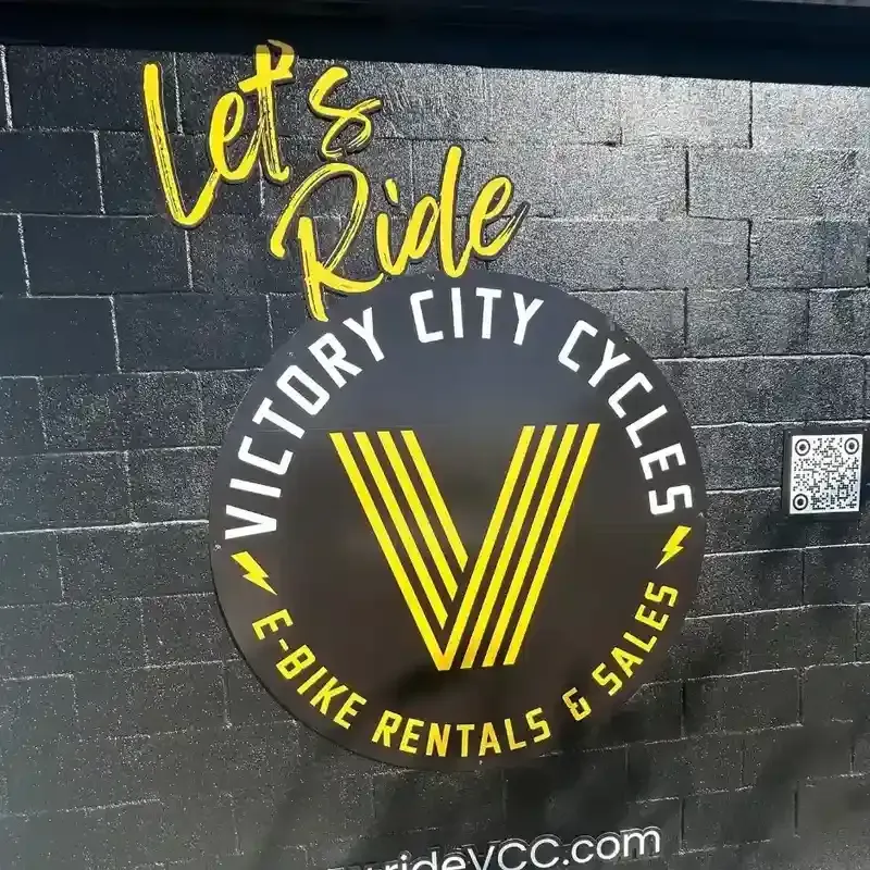 Yellow and black circular window graphic for Victory City Cycles e-bike rentals