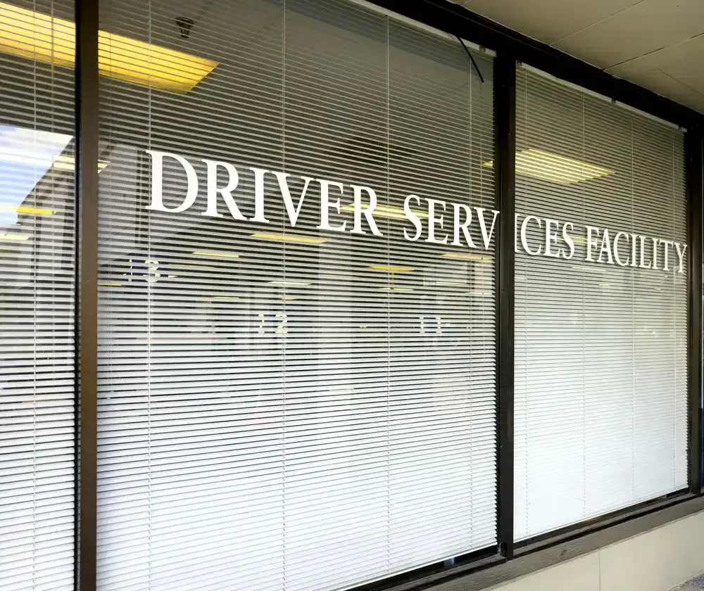 Professional frosted vinyl lettering for a 'Driver Services Facility' applied to large glass office window