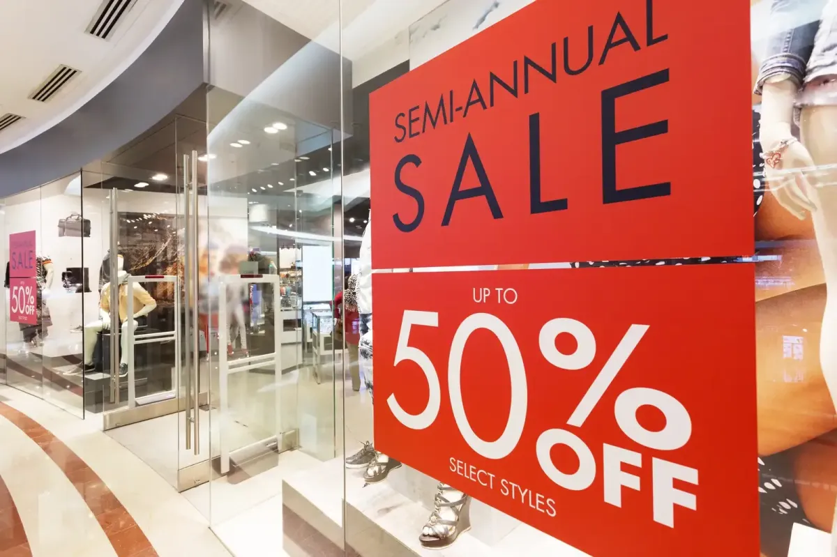 A vibrant red and white semi-annual sale window graphic on a retail storefront, advertising 50% off