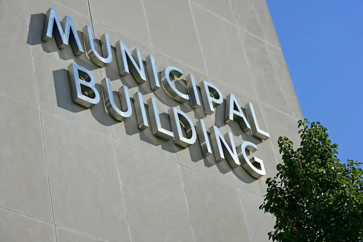 Large-scale silver dimensional lettering for a 'Municipal Building' installed on a light grey textured exterior wall