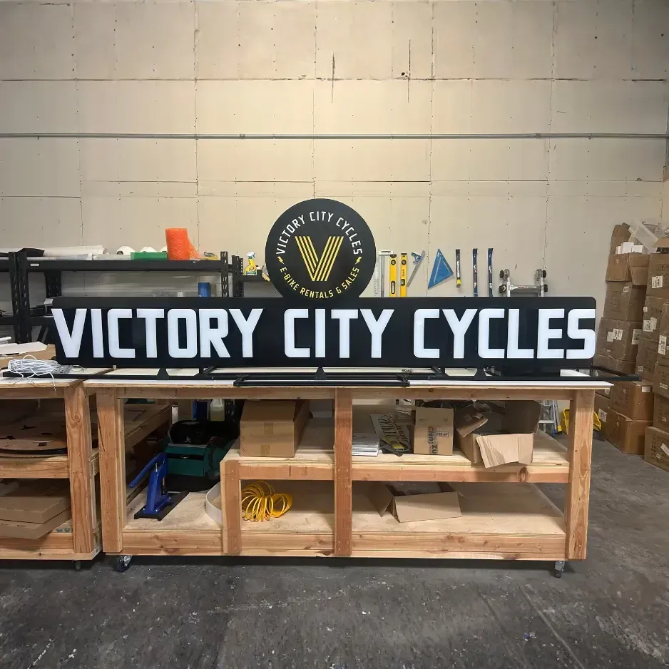 Industrial workshop view of large black dimensional letters for 'Victory City Cycles' being prepared for installation