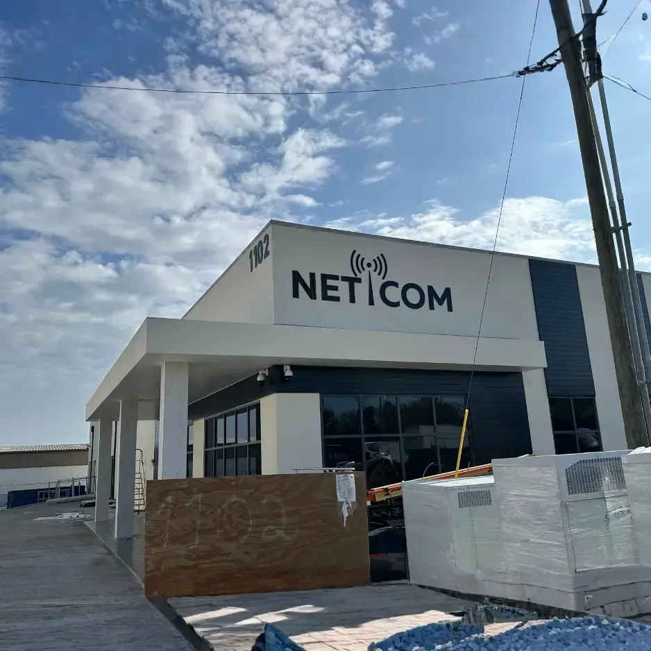 Modern black-and-white exterior building signage for Net.com mounted on a contemporary white facility
