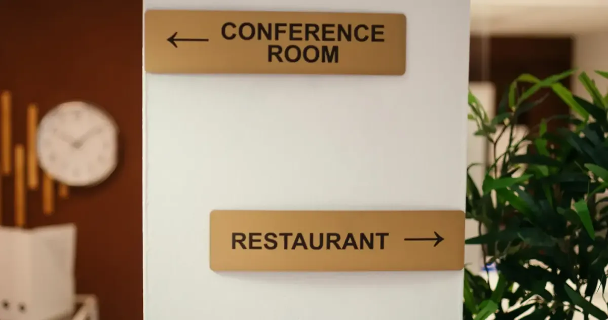 Modern wood-finish directional signs pointing toward a 'Conference Room' and 'Restaurant' in a professional building
