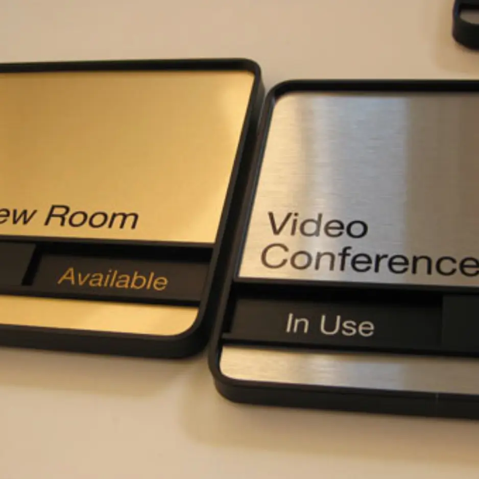 Modern brushed metal interior office signs for video conference room status and room numbering.