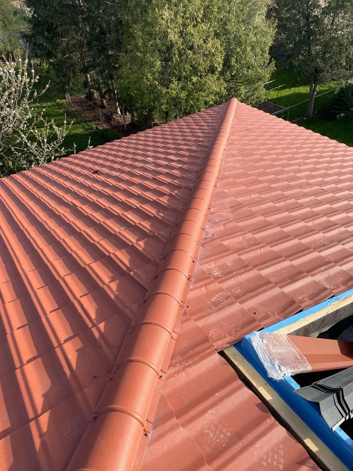 A newly repaired red metal tile roof on a residential home, showcasing expert roofing services and maintenance in Mississauga by Infinity Gutters & Exteriors.