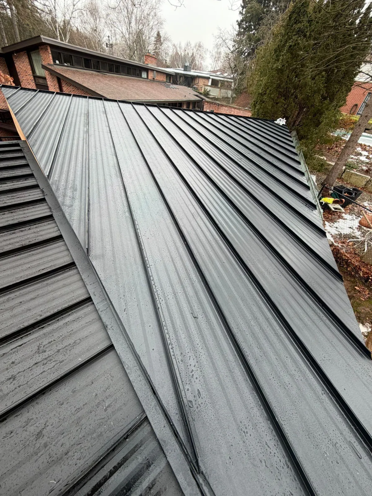 Black standing seam metal roof installation on a modern residential home completed by Infinity Gutters roofing specialists in Ontario