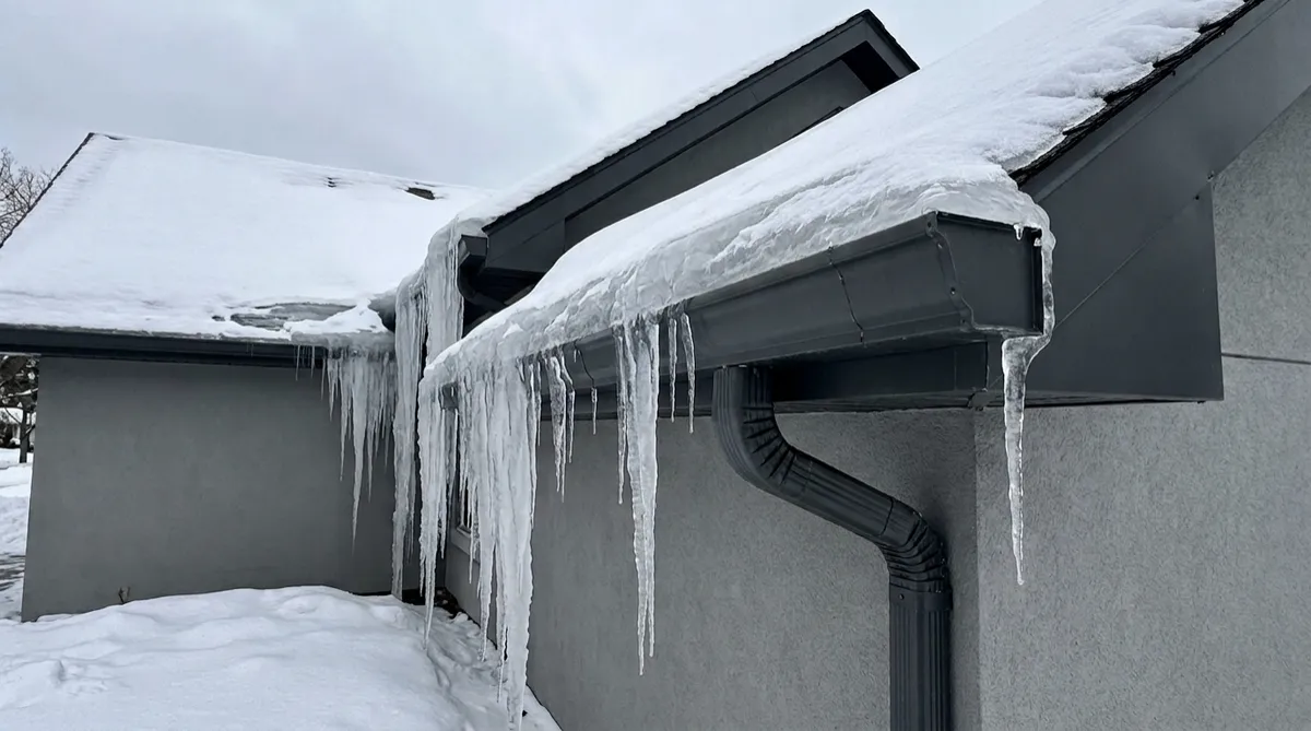 Winter ice dam formation along residential roof eaves and gutters in Toronto GTA.