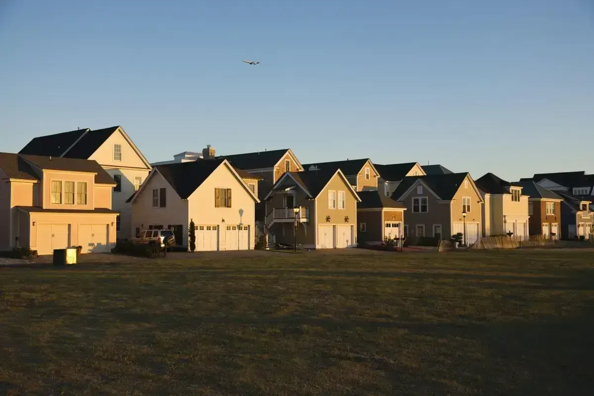 Aerial view of a modern suburban neighborhood with uniform houses and palm trees at a bright, dramatic sunset.