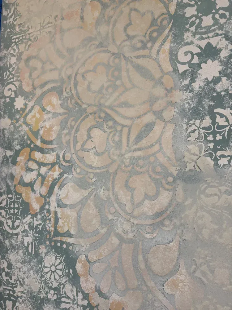 Layered decorative plaster finish with floral pattern, soft metallic tones and handcrafted texture
