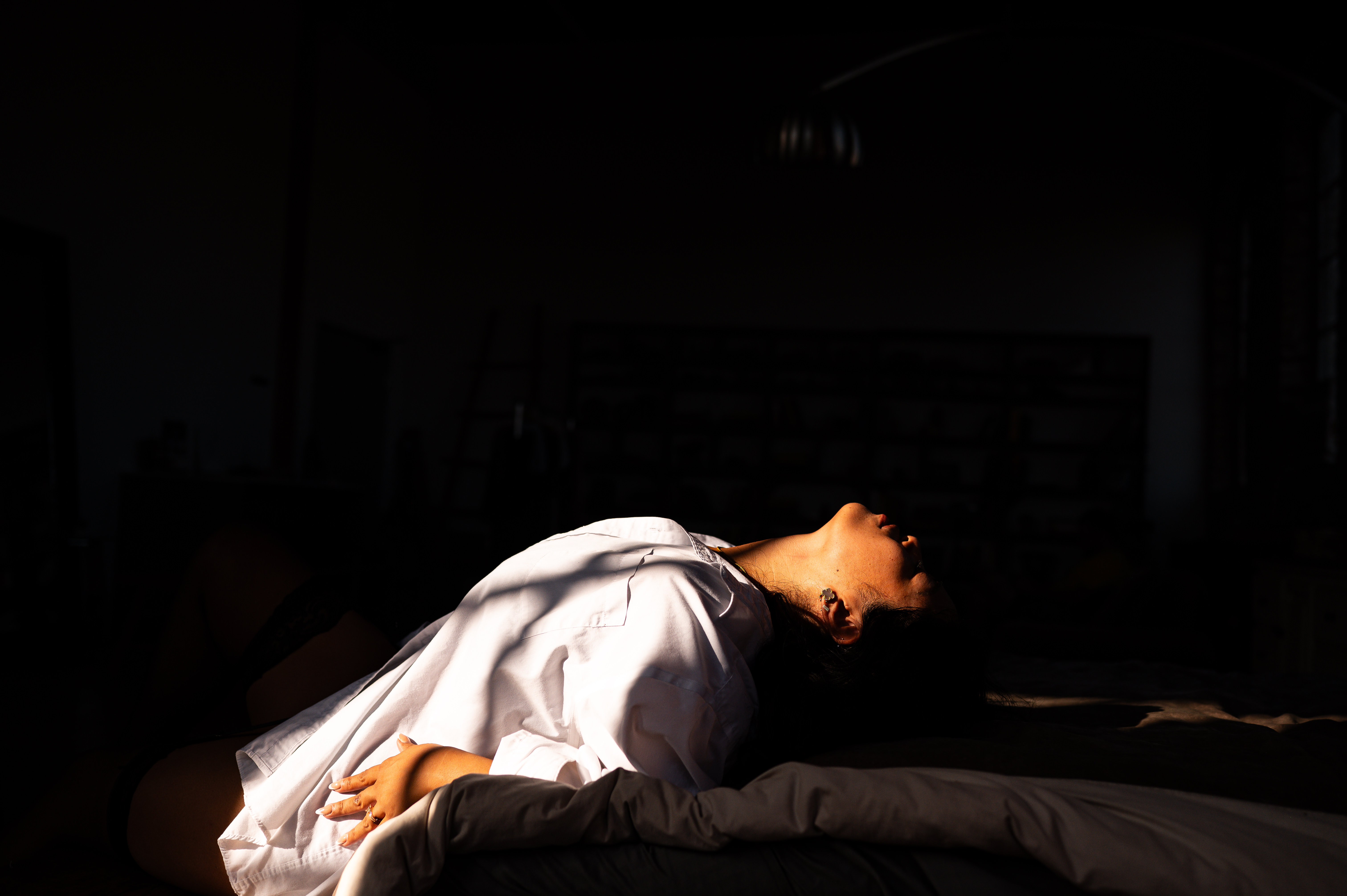ELI Boudoir, Los Angeles boudoir photography. This photograph is of a woman wearing a white button down and thigh high tights. This woman is doing a boudoir pose on a bed. 