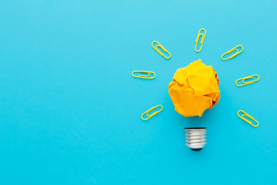 Lightbulb made out of yellow construction paper, with paper clips as the streams of light coming from it.