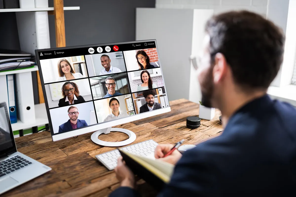 image of a man on a zoom call with a group of participants taking notes