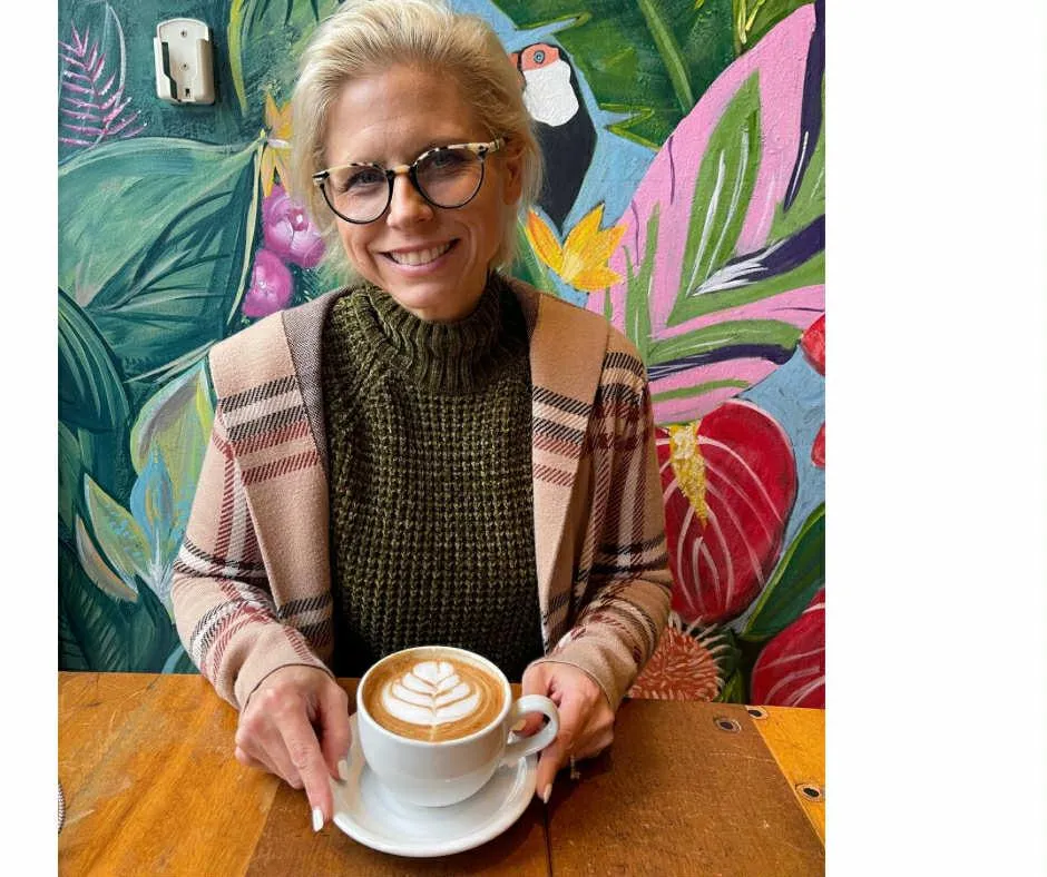 Portrait of Julia smiling in a neutral studio setting, business-casual outfit, soft even lighting.