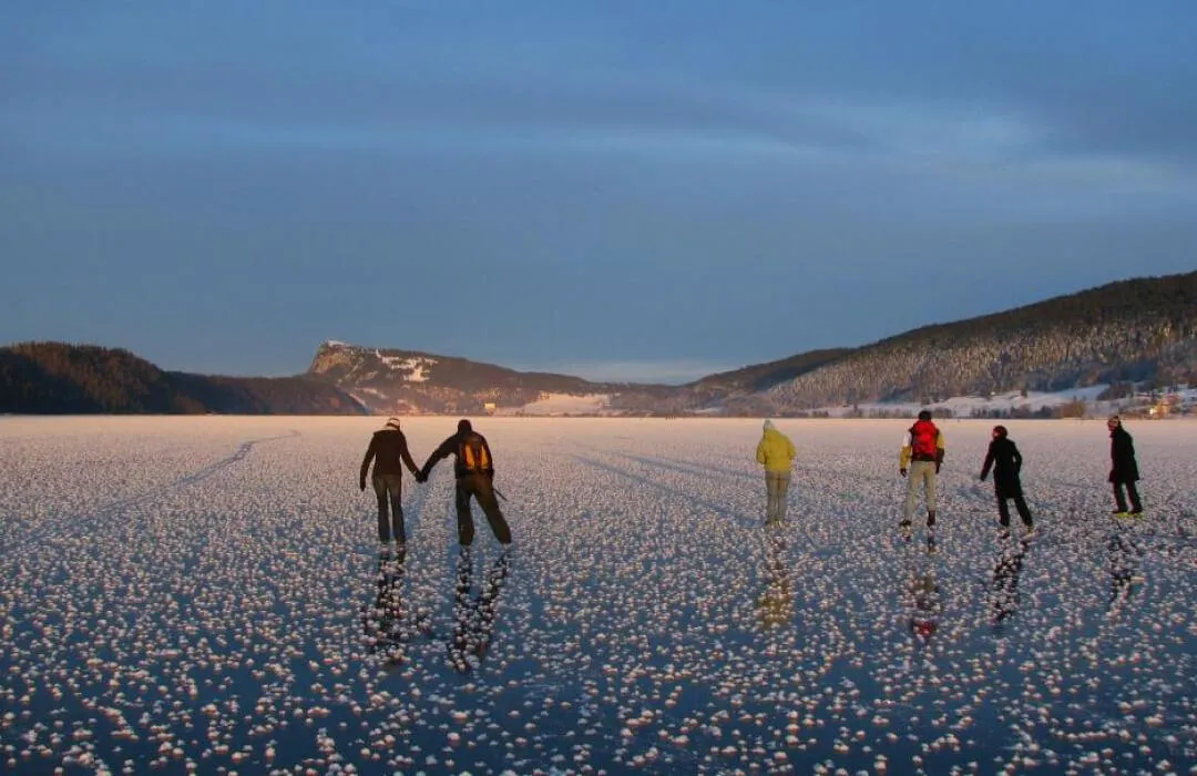 Ice skating on frozen Lac de Joux with snowy Jura landscapes
