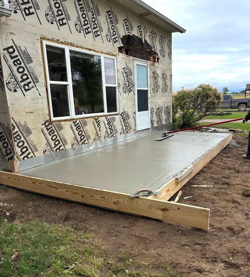 Freshly poured concrete patio slab beside a new home