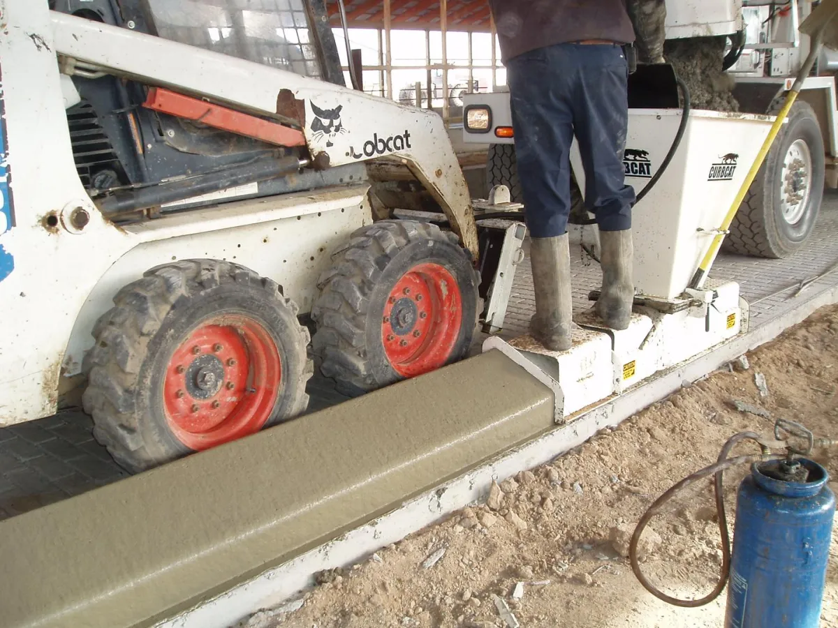 Crew member using a machine to smooth concrete curb