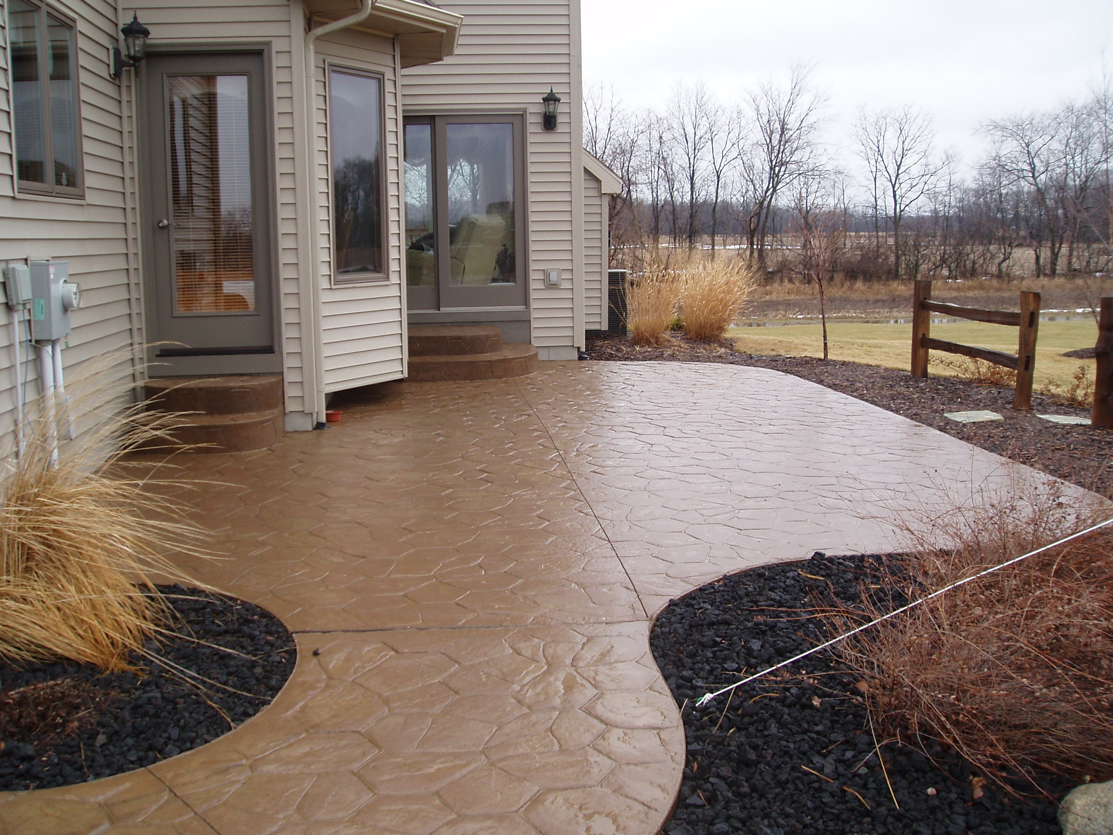 Stamped concrete walkway and patio beside a home