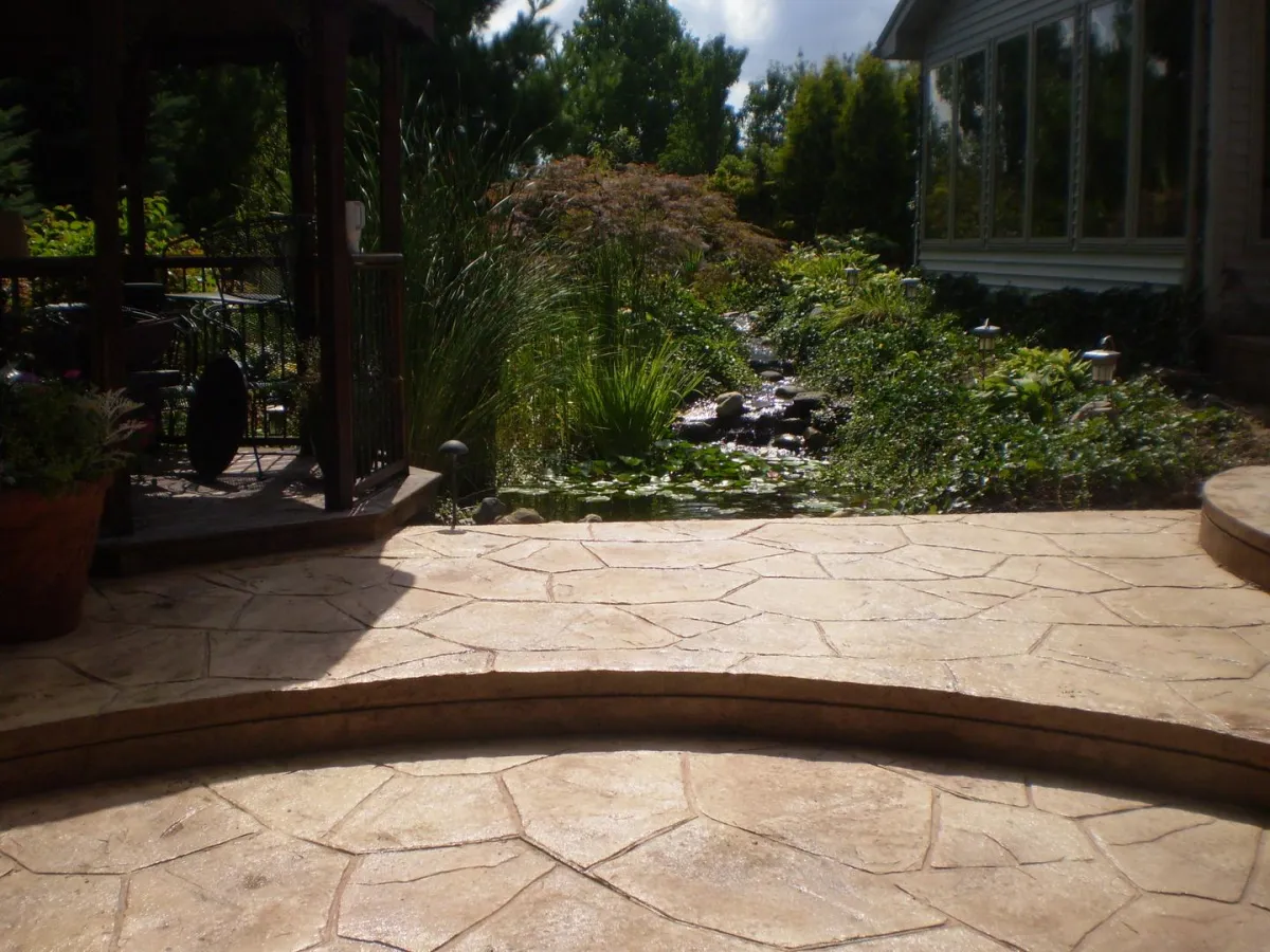 Curved stamped concrete patio with landscaped garden beds