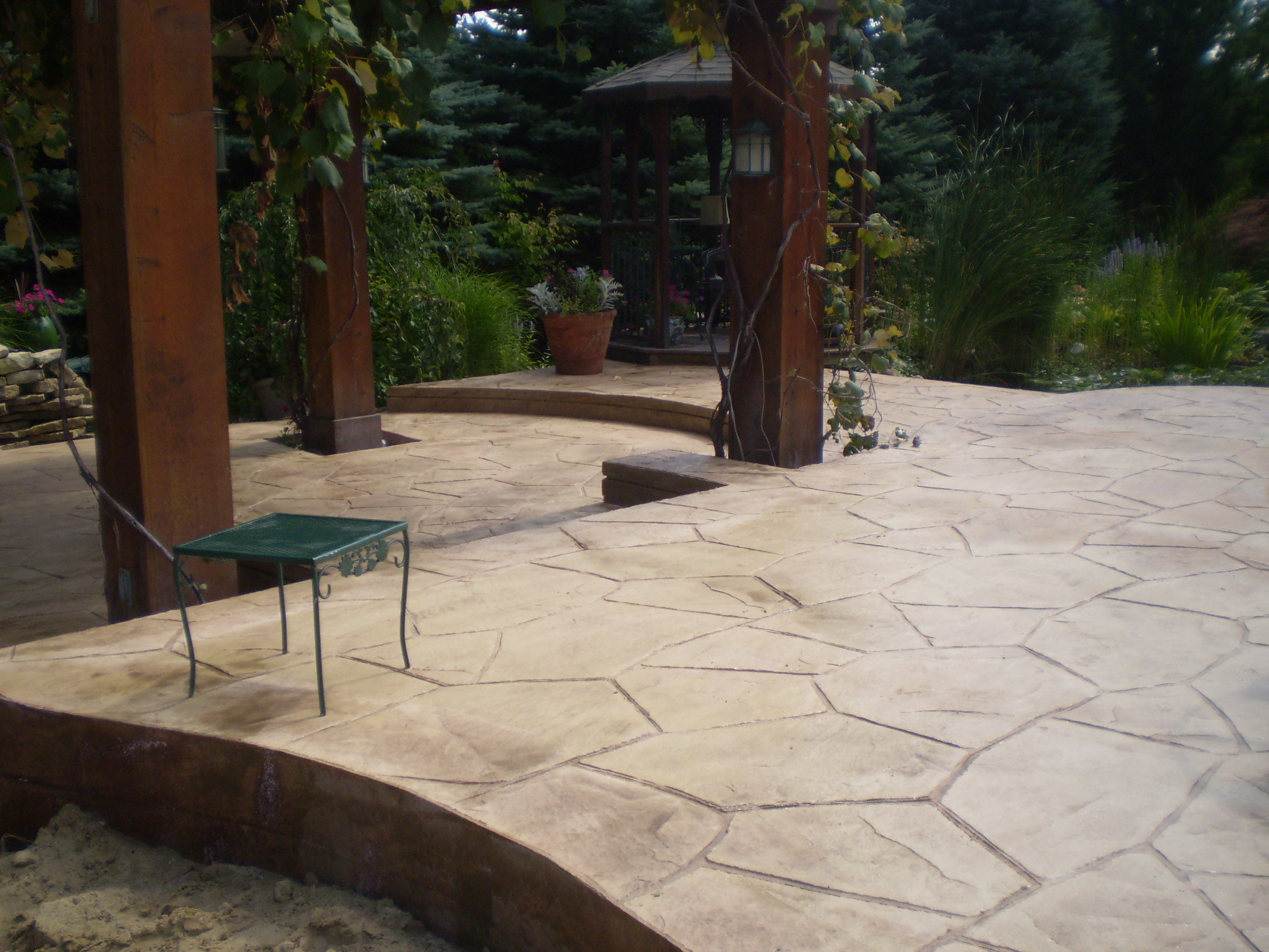 Stamped concrete patio beneath a backyard pergola