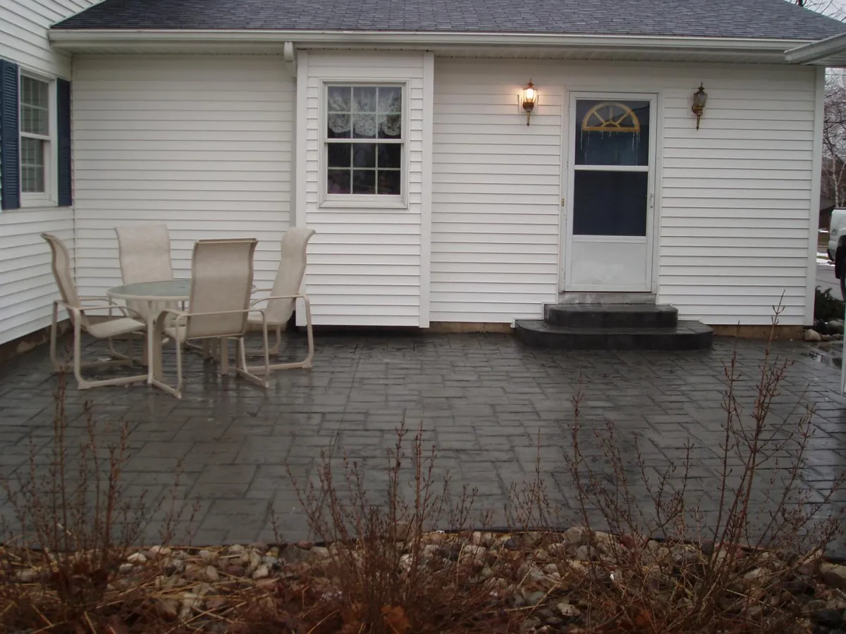 Dark stamped concrete patio outside a residential back entrance