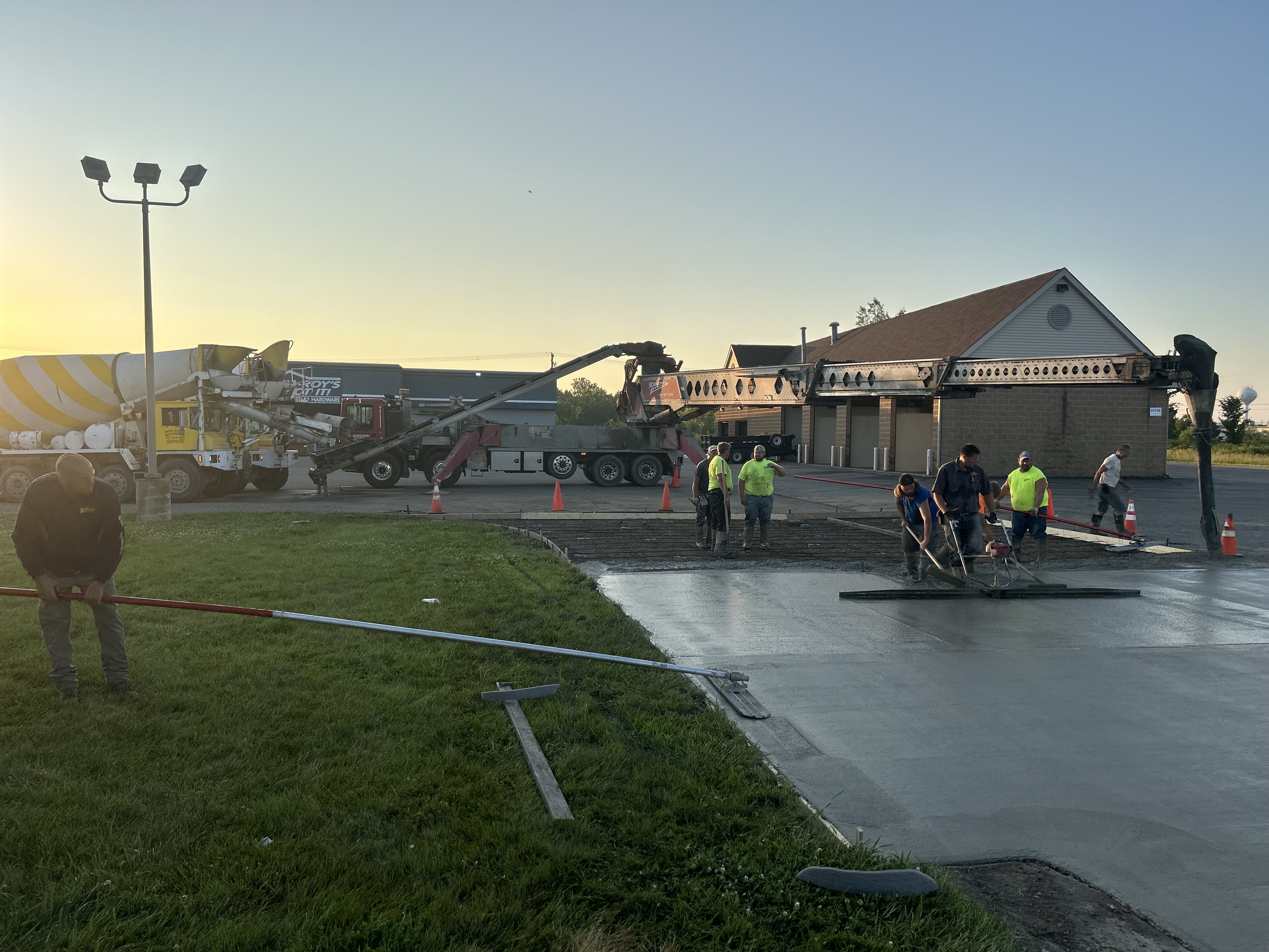 Crew smoothing wet concrete at commercial project site