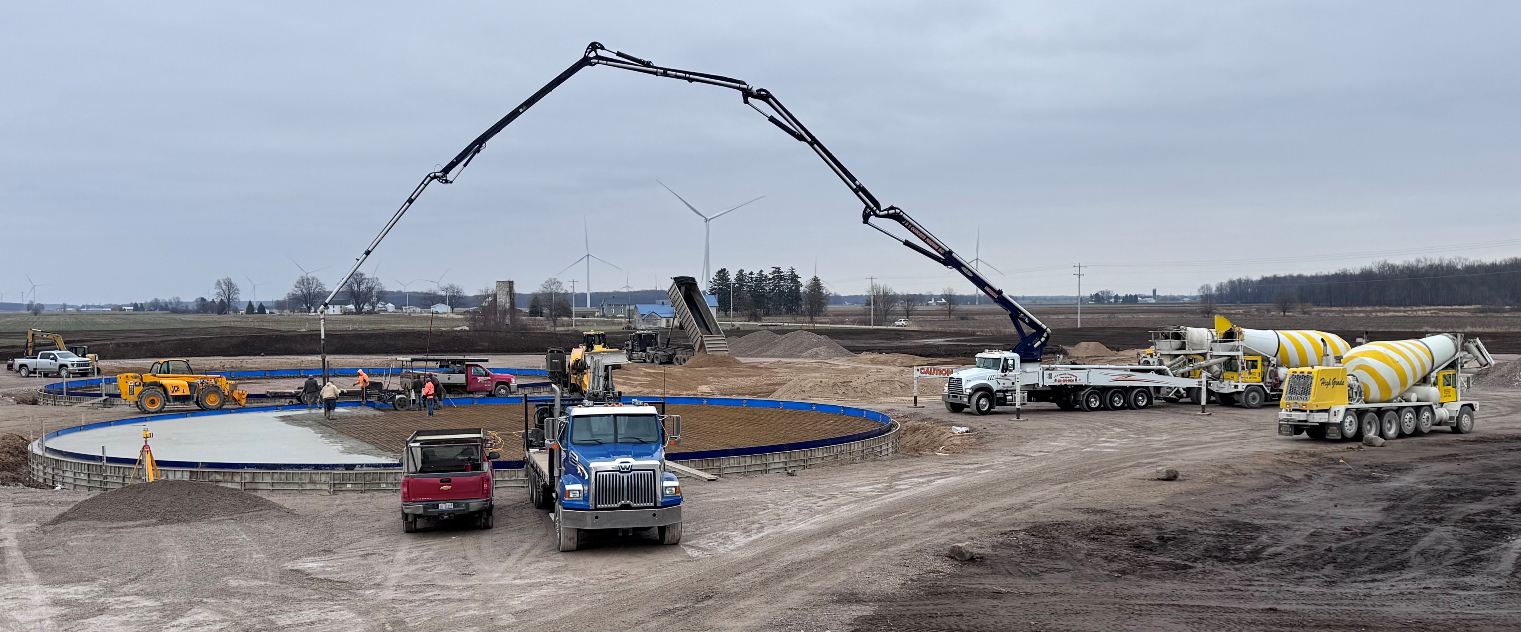 Various trucks and concrete pouring equipment at an agricultural project site