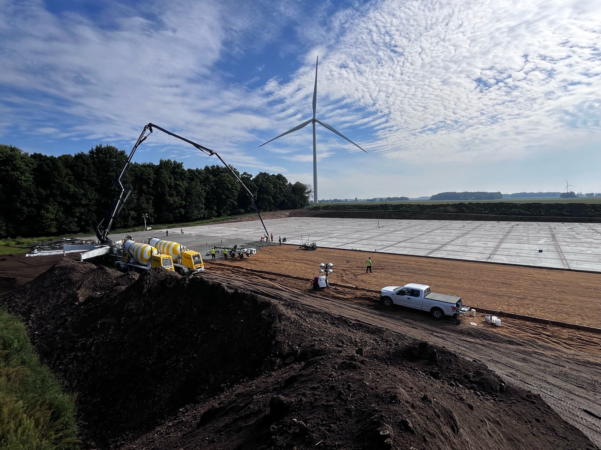 Large expanse of smooth concrete with more being poured by crew with special equipment