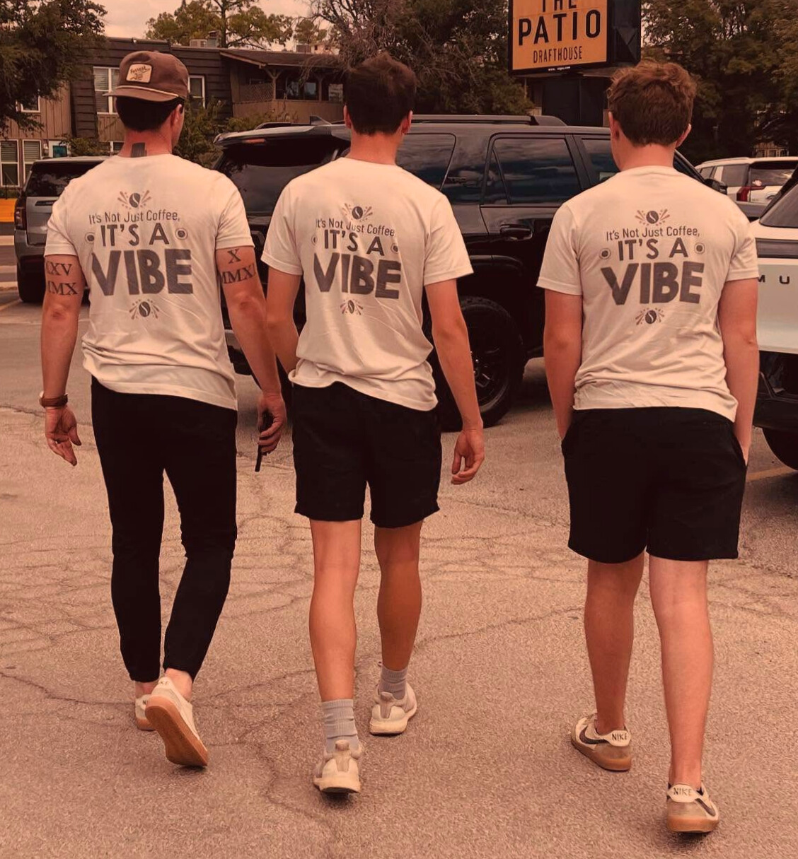 Three Vibes 2 Go team members walking together wearing matching ‘It’s Not Just Coffee, It’s a Vibe’ shirts outside in Midland, Texas.