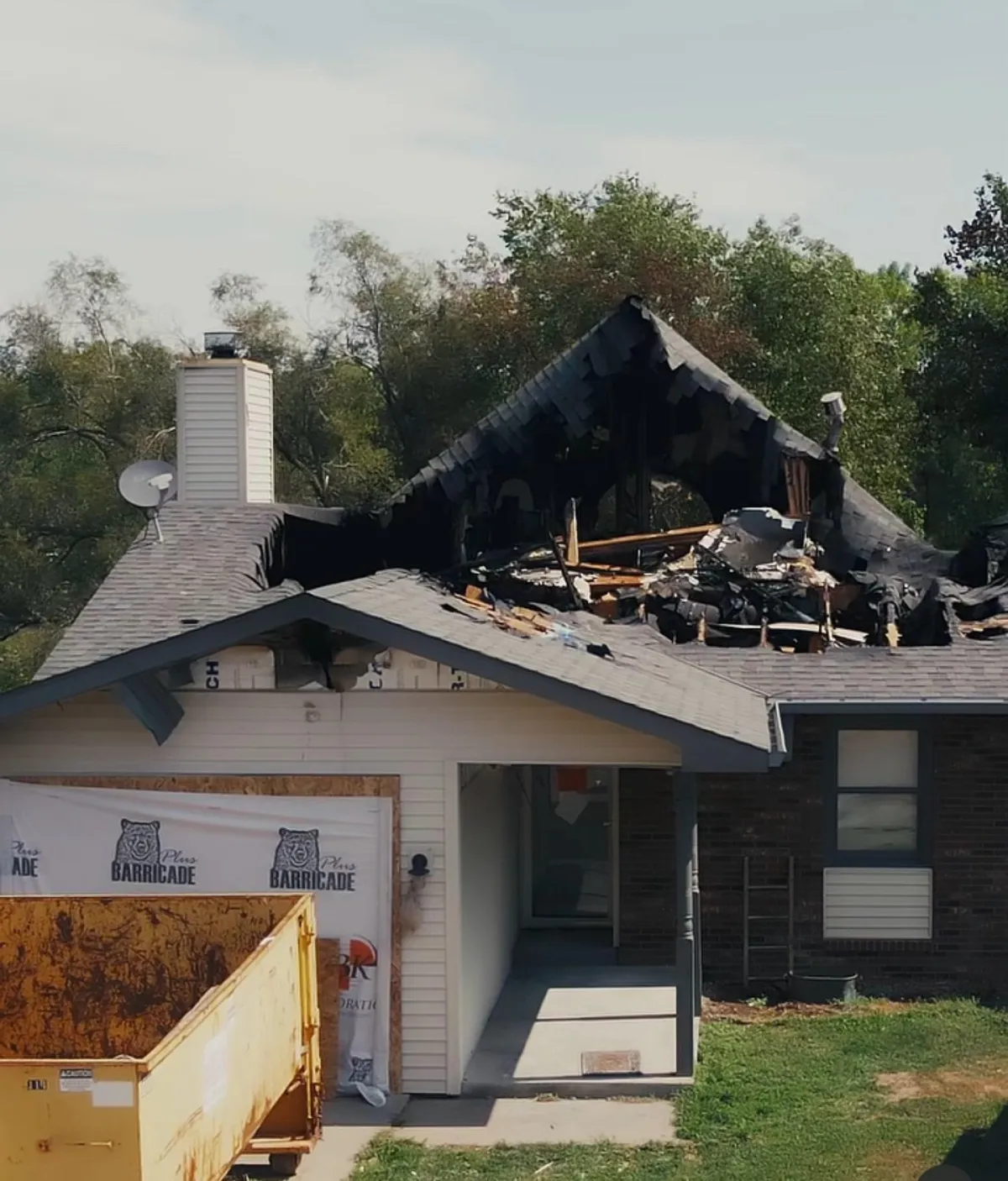 A house with a severely damaged roof and debris scattered around