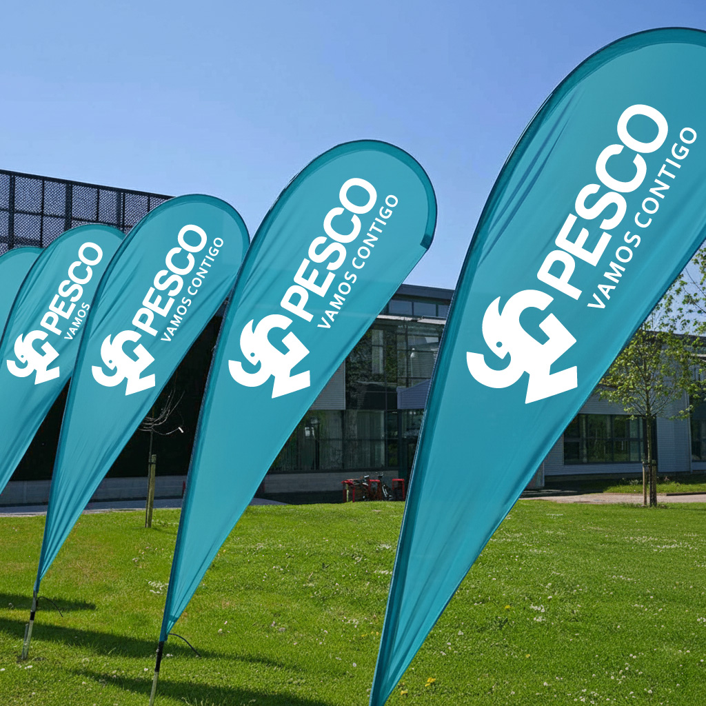 Bandera tipo gota - Landscape product image of a teardrop flag mounted outside a retail store showing scale against the storefront and footpath, evening ambient light and clear brand print visible.